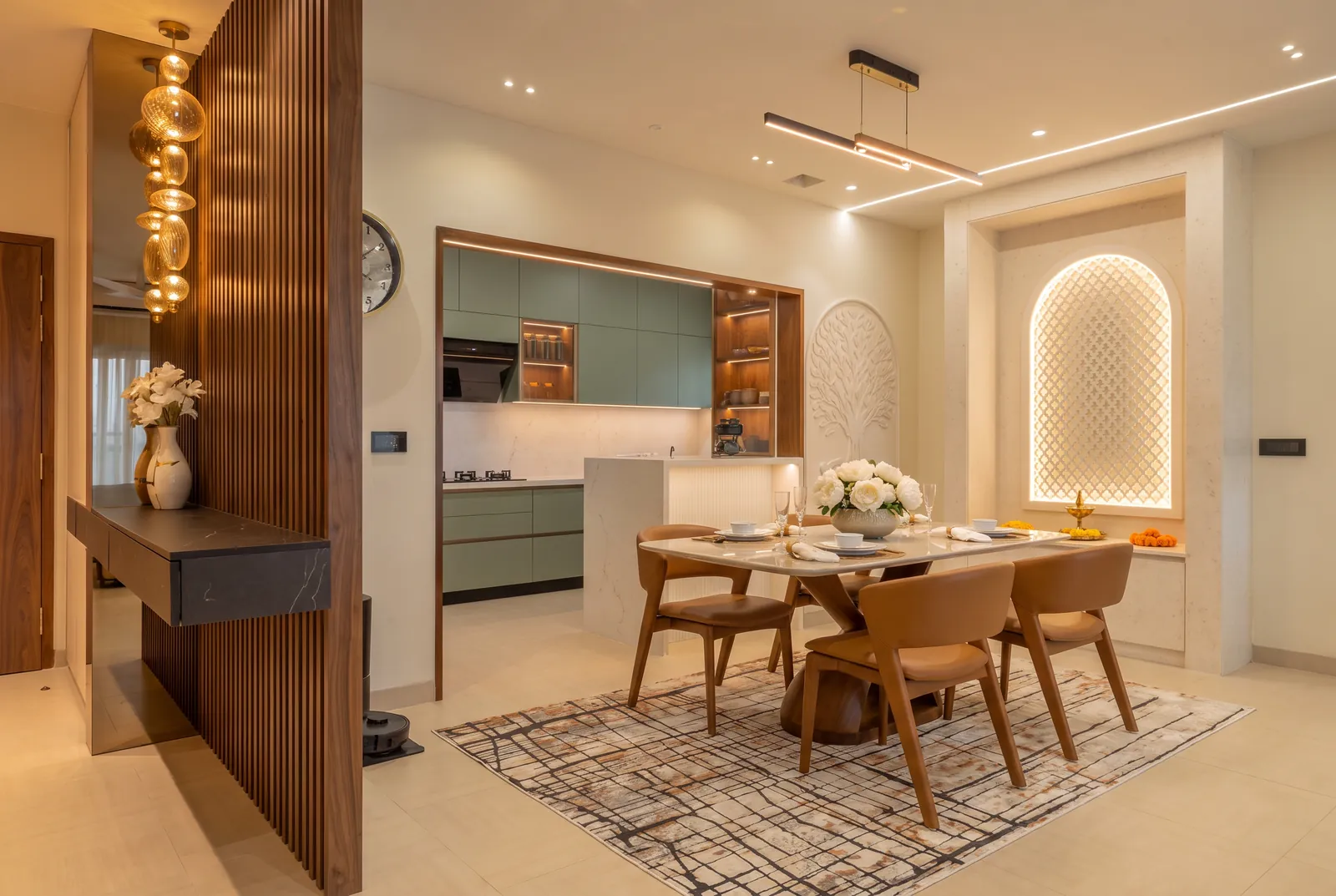 A dining room with a fluted walnut screen, a sage-green kitchen and a backlit jaali pooja niche.